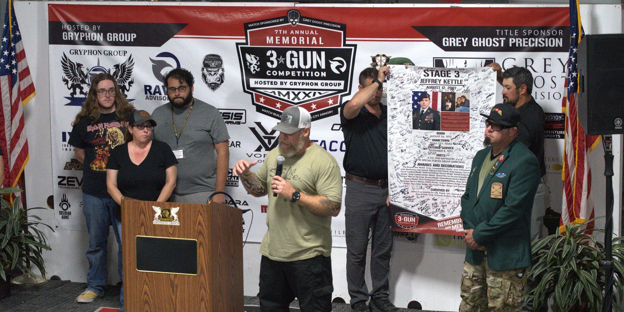 A Gold Star family is honored on stage as their hero's signed banner is presented at the 2024 Memorial 3 Gun