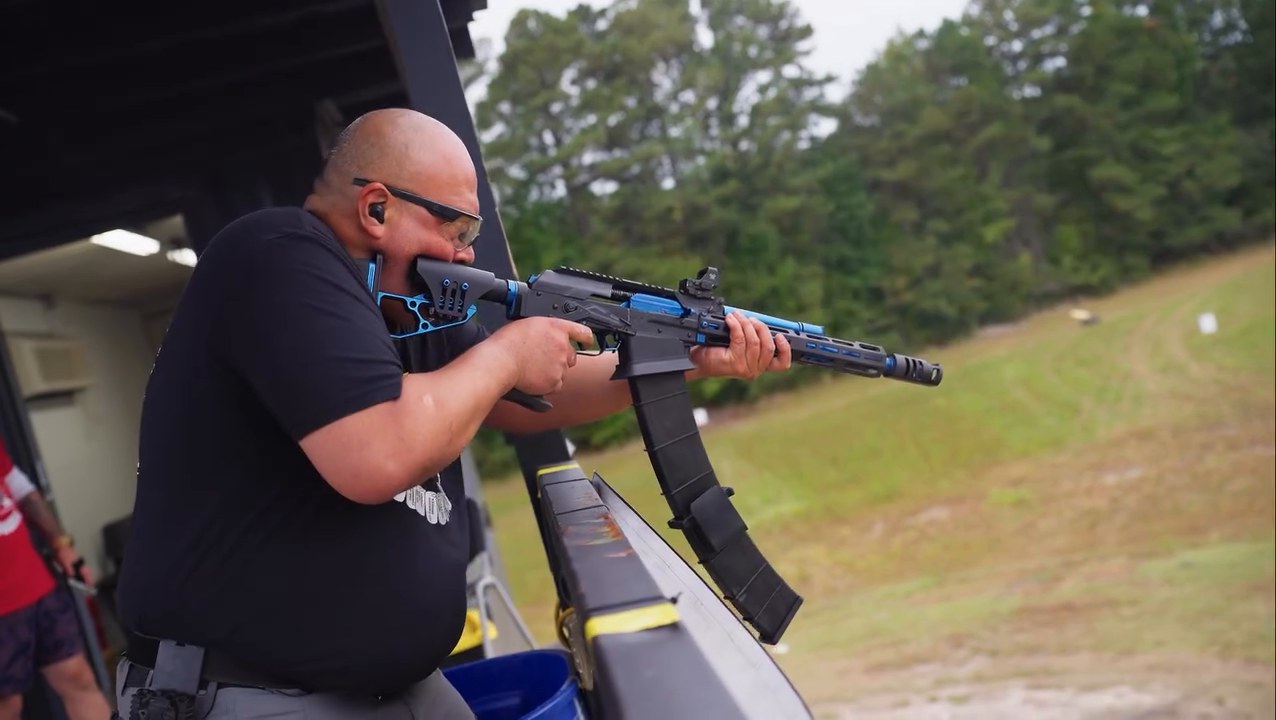 A competitor shoulders his rifle from a vehicle stage