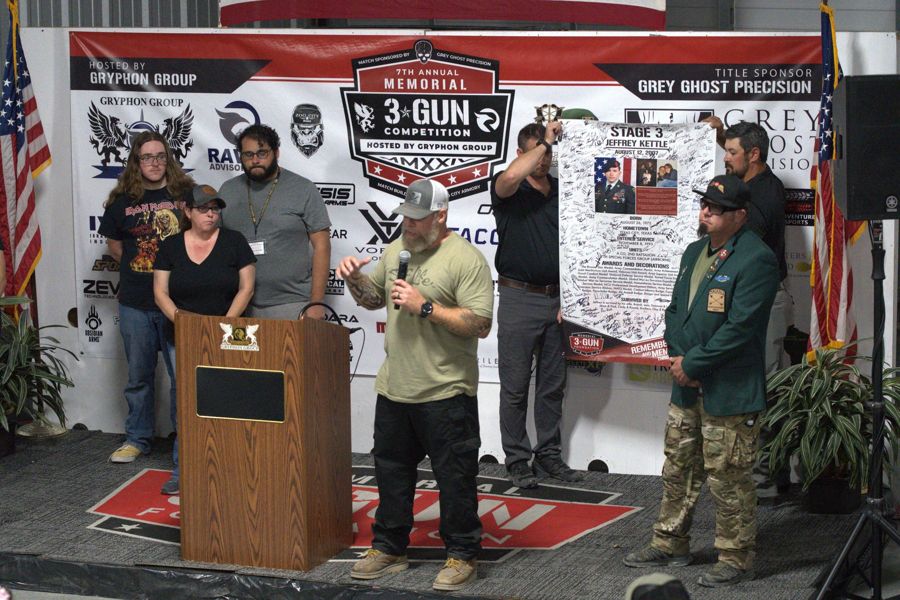The Kettle family is honored on stage as the signed Stage 3 banner for SFC Jeffrey D. Kettle is presented at the 2024 Memorial 3 Gun