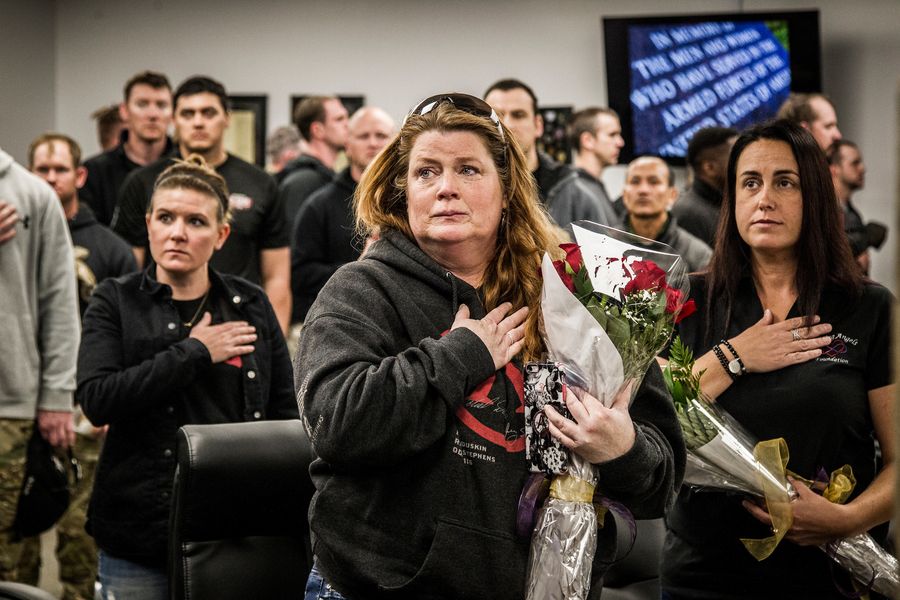Maggie Duskin, wife of CW2 Michael S. Duskin, and her friend Louise Cantrell hold roses with hands over hearts during the honors ceremony at the 2018 Memorial 3 Gun
